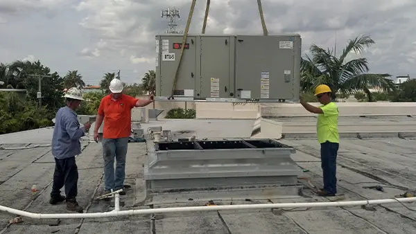 Workers installing an external HVAC unit, showing multiple people collaborating on the project.