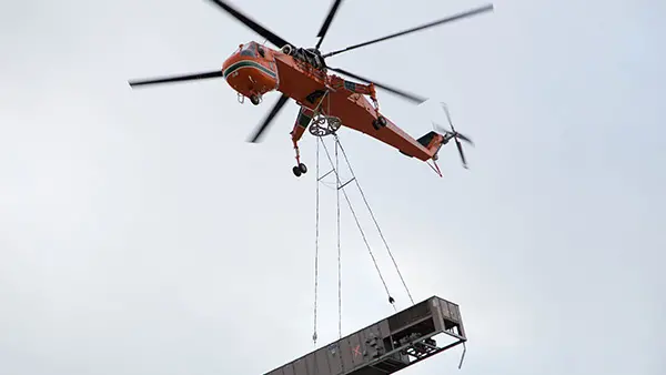 Helicopter lifting an HVAC unit for transport.